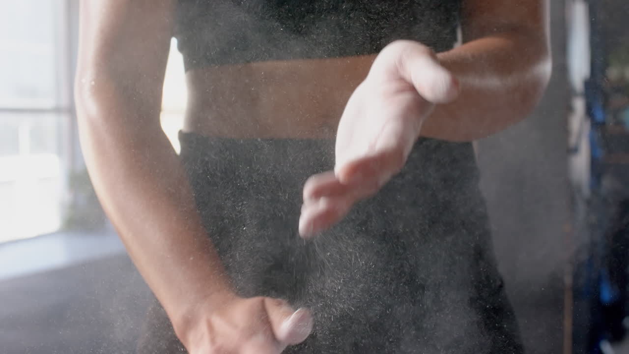 Clapping hands with chalk dust, woman preparing for workout in gym