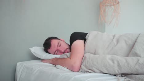 sleeping man, caucasian white with beard, young man lying in bed sleeping dreaming, uncomfortable pillow, turn over in sleep