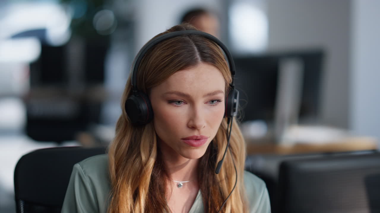 Nærbilde av kvinnelig resepsjonist med headset for konsultasjon som ser på datamaskin på kontoret