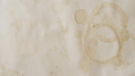video de un primer plano de un pedazo de papel con manchas redondas de taza de café sobre un fondo blanco