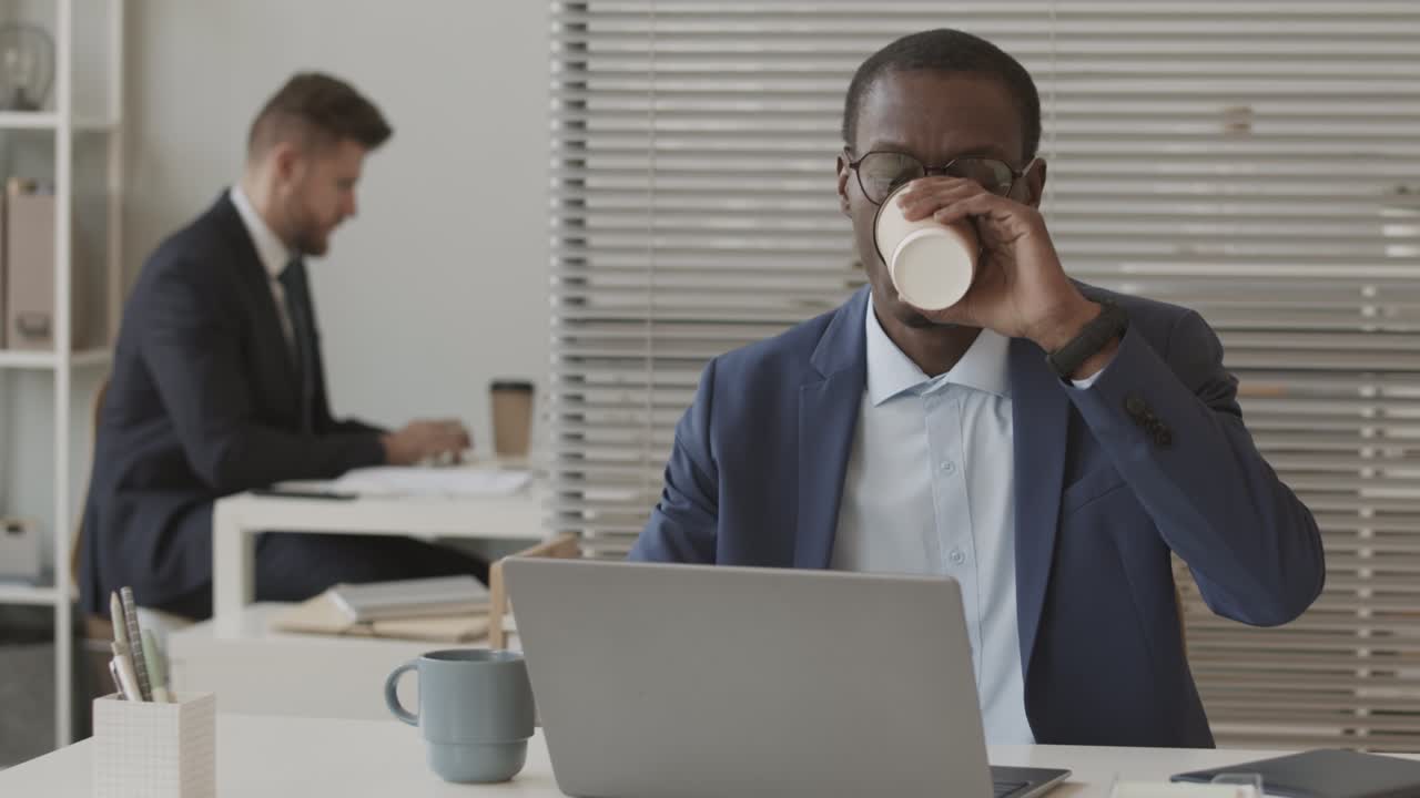 Corretor afro-americano trabalhando no laptop no escritório