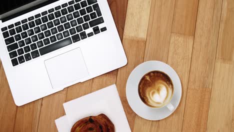 Close-up of laptop with coffee cup and sweet cookie