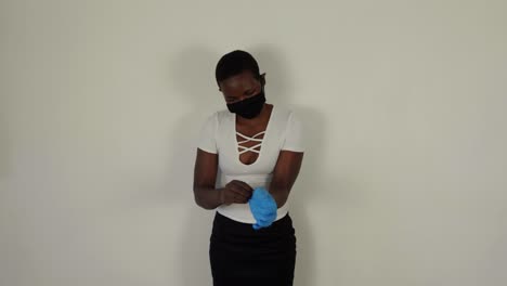 african lady putting on blue gloves while wearing a mask for covid-19