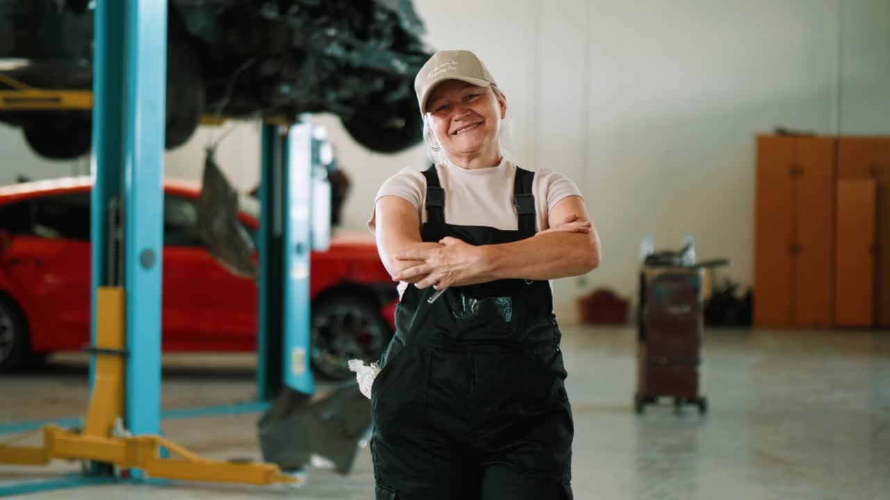 mujer mecánica confiada de pie y mirando a la cámara en el garaje de automóviles. retrato