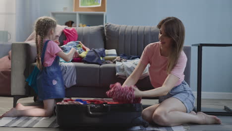 Happy-mother-and-daughter-gather-belongings-into-suitcase