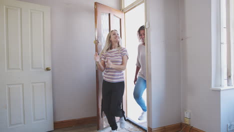 excited female couple opening front door of new home