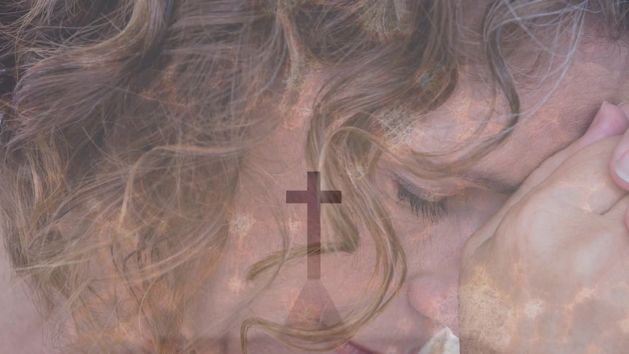 Mature woman holding hand near face in close-up, cross and cloud light fading over face, praying