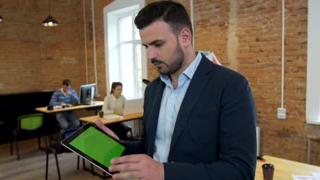 man using black tablet with green screen at modern office. chroma key. close up.