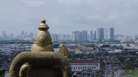 kartikeya statue overlooking kuala lumpur skyline with cloudy sky, southeast asia, malaysia.