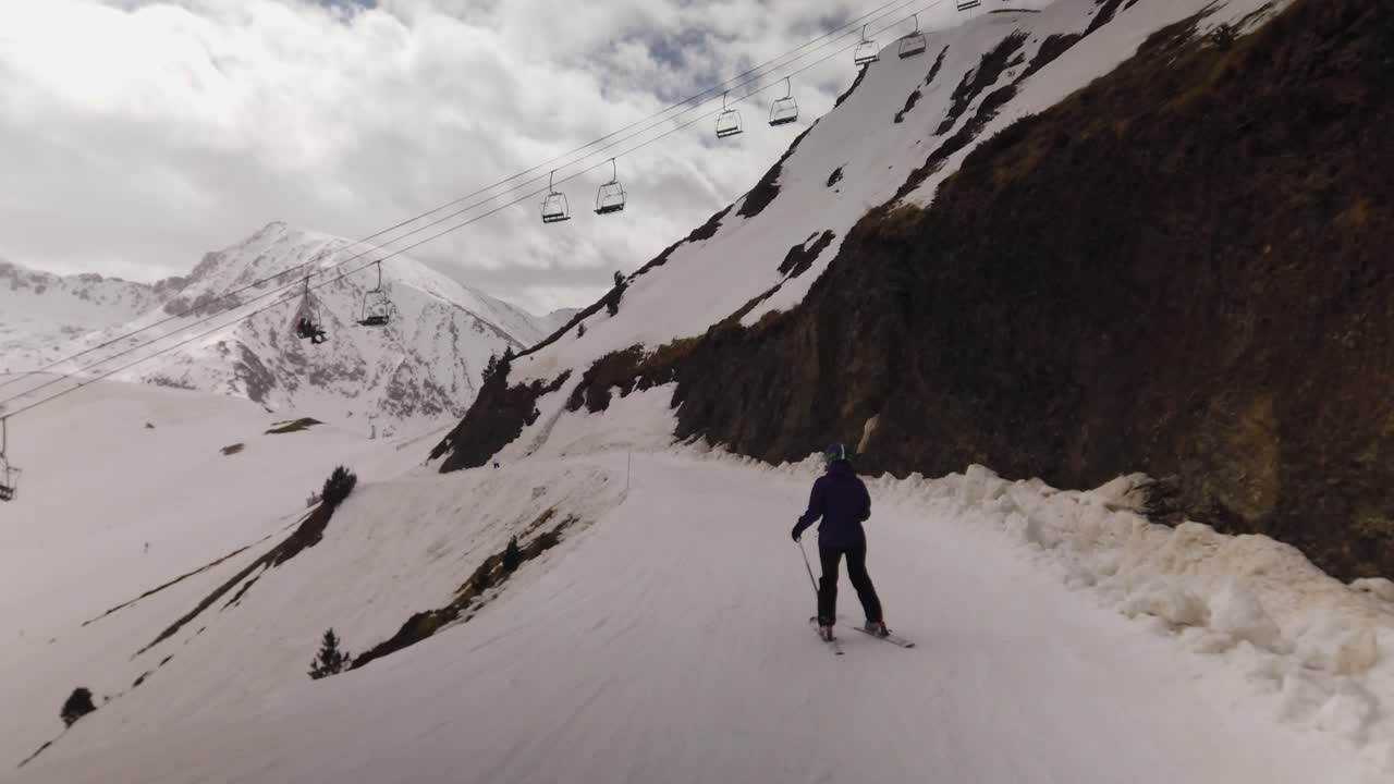 여성 스키어를 따라 좁은 트랙을 내려가 체어리프트 아래를 지나가는 샷