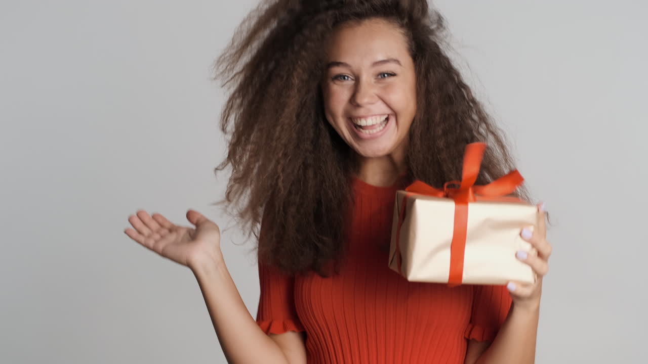 행복한 백인 곱슬머리 여자가 선물을 받습니다.