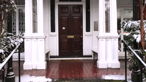 home sweet home - snowy scene coming in out of the cold entering a wooden front door into a mansion house