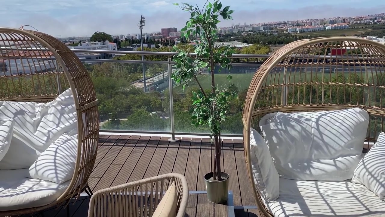 Sedie di legno vuote disposte su un'elegante terrazza all'aperto in cima a un grattacielo, che offre un ambiente sofisticato e panoramico.