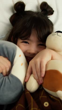 a happy child lying in bed with stuffed animals