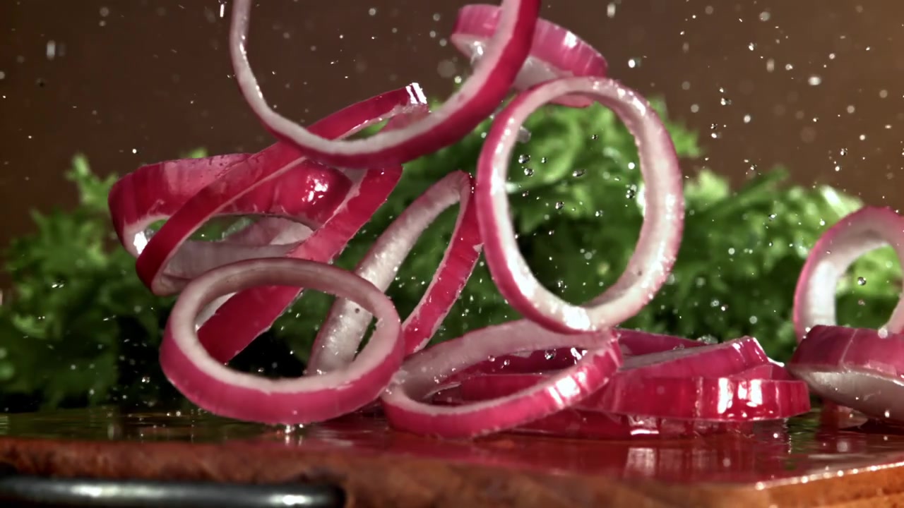 Slow Motion of Red Onion Rings Falling onto Wet Cutting Board