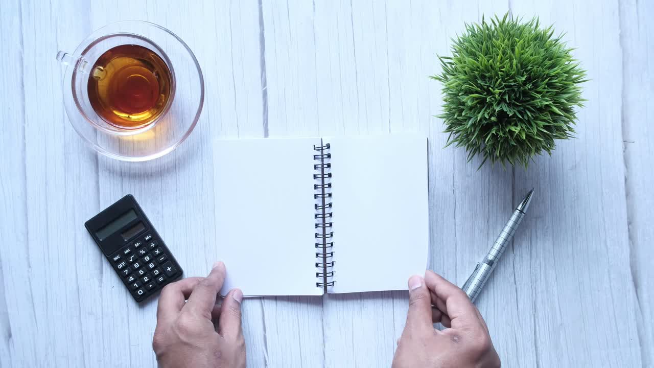 계산기 와 차 를 가진 사람 이 책상 에서 노트북 을 열고 있다