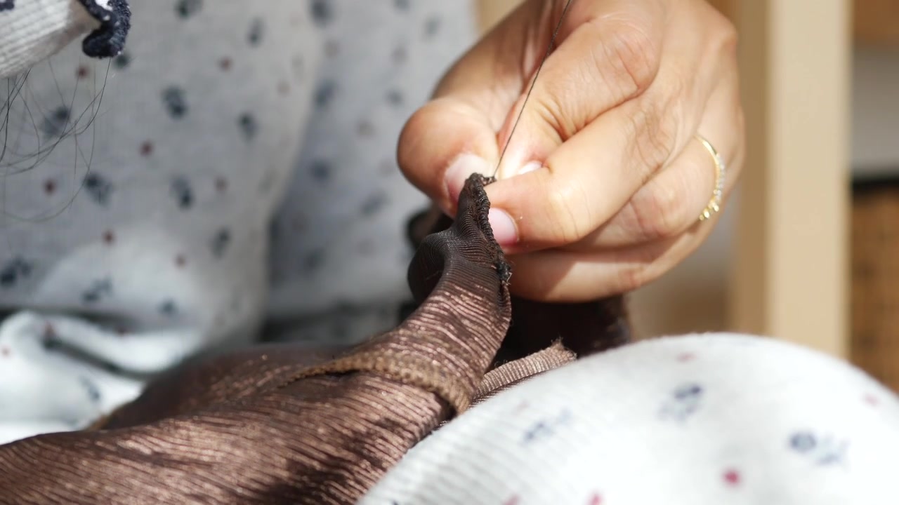 Close-up of Hands Hand-Sewing Brown Fabric