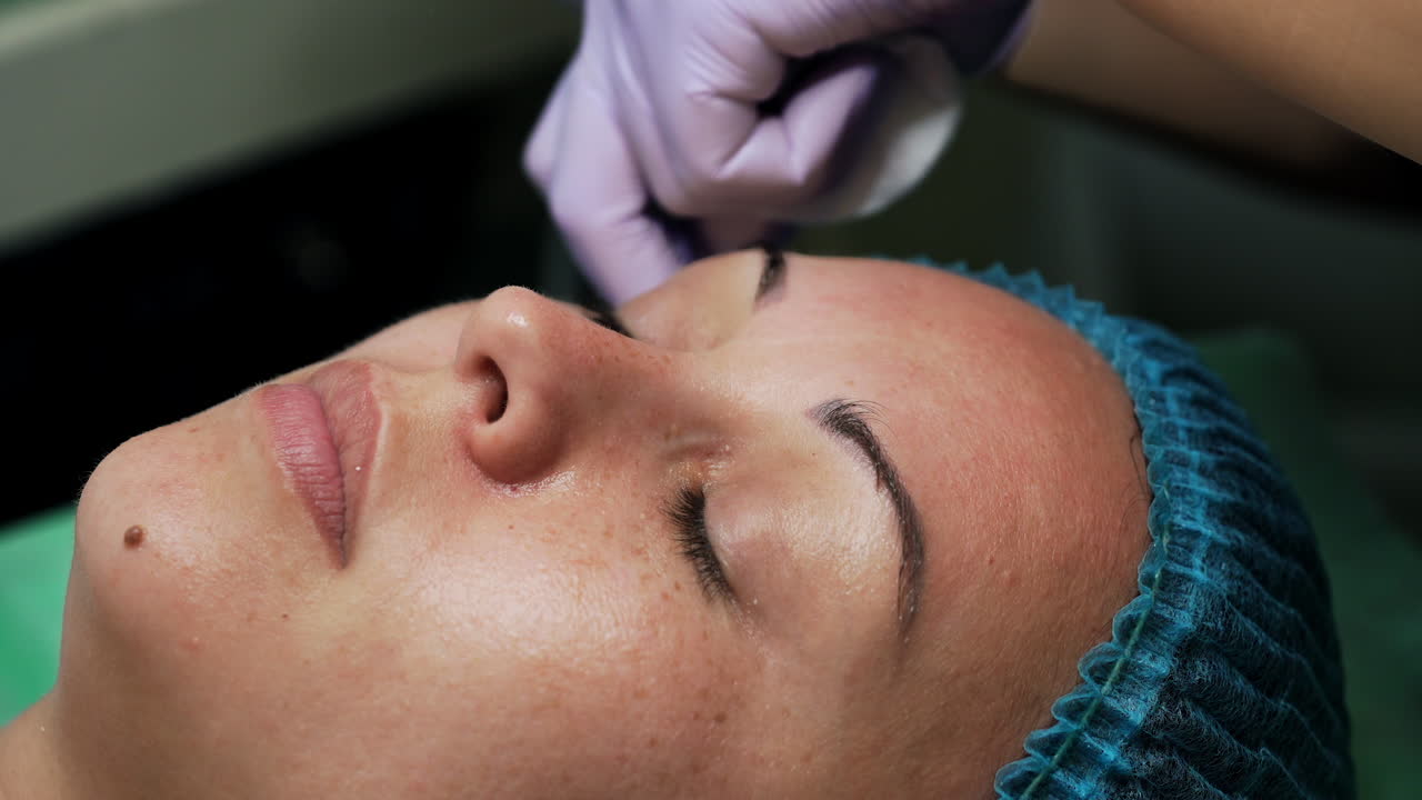 Woman having a procedure of face cleansing. Cosmetologist uses special ultrasonic scrubber for skincare. Extreme close up.