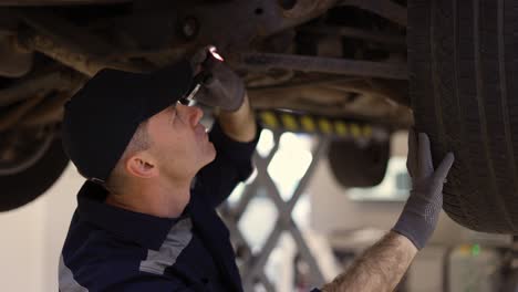 Car-service-worker-examining-car-fails-with-lighter-in-hands