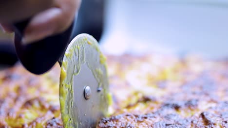 close-up-shot-of-a-pizza-cutter-cutting-delicious-tasty-home-made-gourmet-pizza