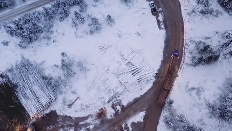 Un-Dron-Aéreo-Disparó-Un-Camión-De-18-Ruedas-Cargado-Con-Unidades-De-Madera-De-Pino-Maduras-En-Caminos-De-Tierra-En-Un-Campamento-Maderero-De-Invierno-Cubierto-De-Nieve,-Antes-Del-Amanecer-3