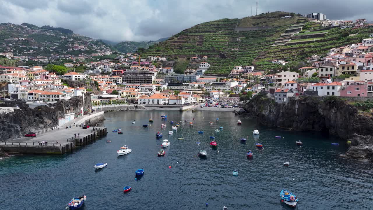 Aerial dolly over local fishing boats in harbor of Câmara de Lobos on Madeira