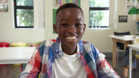 in school, african american boy holding pencil, smiling while participating in classroom activities