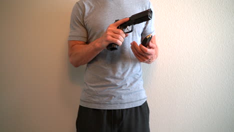 angry man loading a magazine full of bullets into a semi automatic handgun