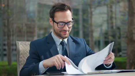 Millennial-businessman-sit-in-a-park-reading-message-phone-with-good-news-smiling-feels-happy-enjoy-moment-of-getting-great-offer,-satisfied-with-sales-report,-growth,-talking-himself-turning-pages