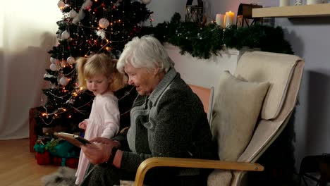 elderly woman reads the message on the tablet