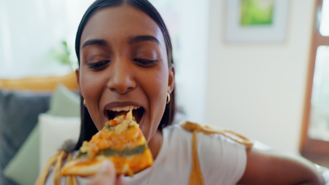 Pizza, face and a hand feeding a woman on a sofa
