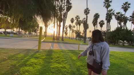 girl walking at santa monica venice beach during golden hour with beautiful californian palm trees