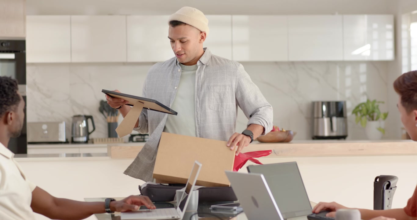 African American man placing box, opening it, showing framed plaque to team in kitchen