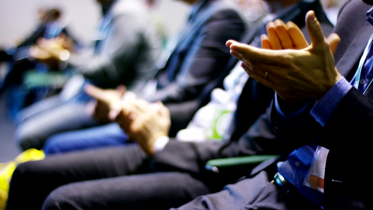 close up of people sited and listening to a business conference.