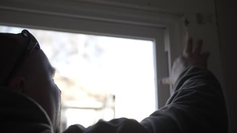 a man works inside remodeling a house - seals window trim