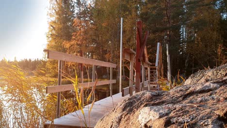 Tourist-boy-on-hiking-trail-in-national-park-in-Finland,-walking-alone-over-wooden-bridge,-beautiful-lake-nature-scenery