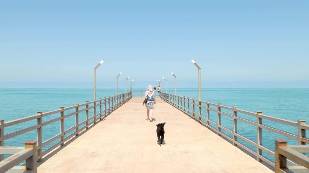 Girl walking with the funny small dog on the pier. Batumi, Georgia