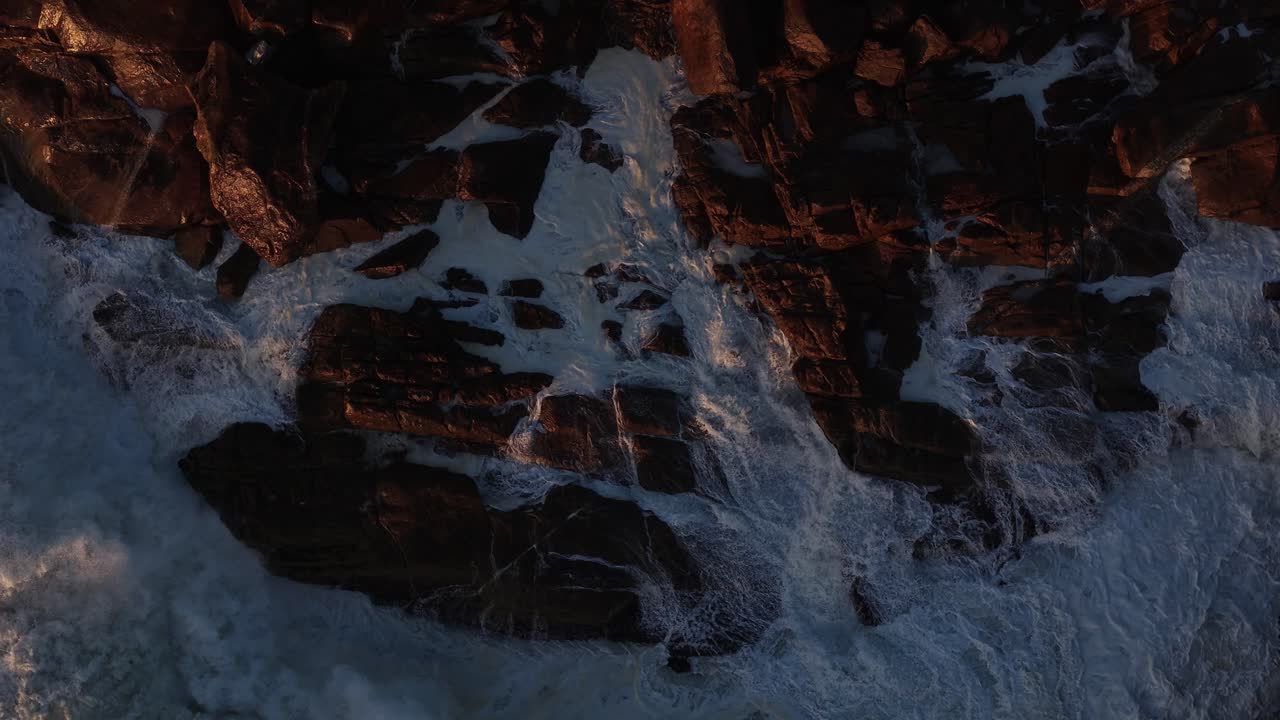 Waves hit the shoreline rocks in slow motion