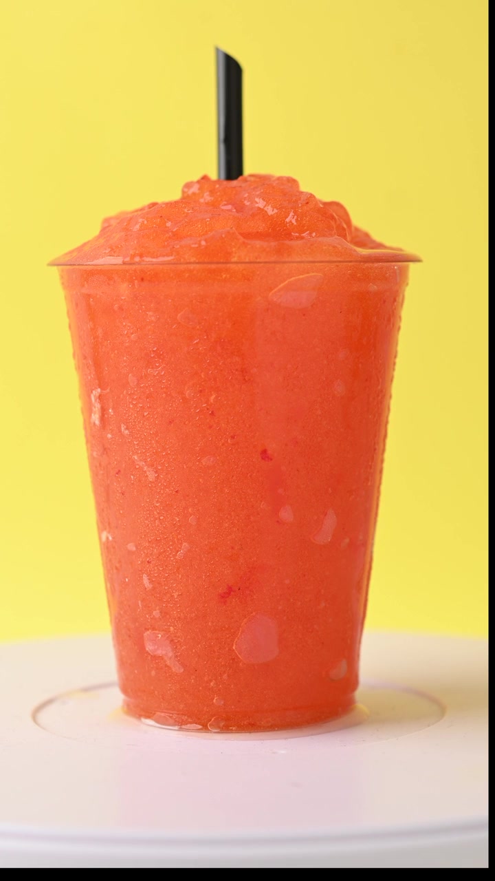 Granita ai frutti rossi in bicchiere di plastica su sfondo giallo