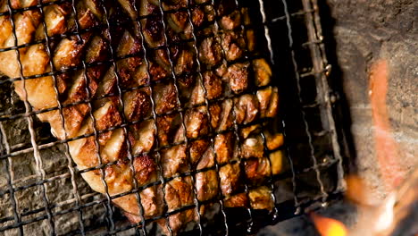 juicy lamb rib being barbecued till crispy, fat dripping, heat from open fire