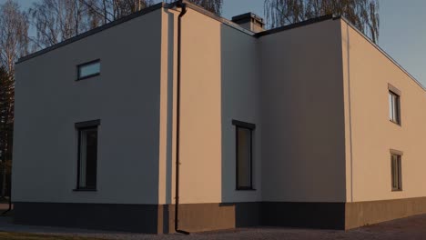 warm sunset light illuminates the facade of a modern minimalist house, casting long shadows and highlighting the clean lines and geometric shapes of the architecture
