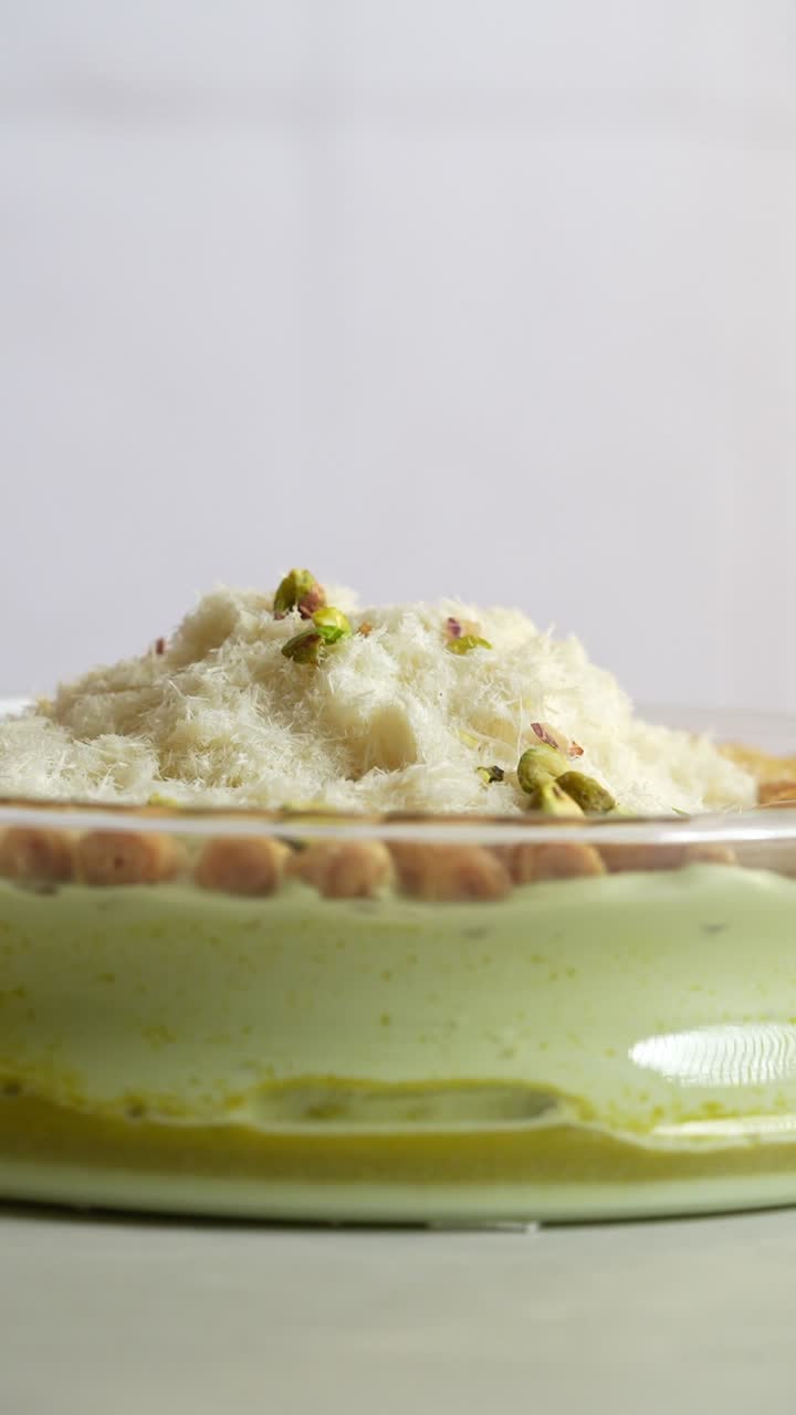 A chief puts nuts on a cake with sweets, close up shot,