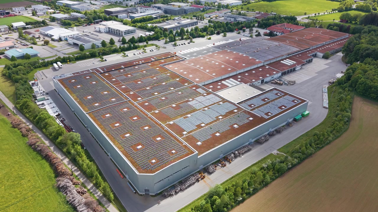 Luftfoto af industrielle fabriksbygninger med solpaneler på taget i Tyskland, der viser bæredygtig produktion og integration af vedvarende energi, UHD