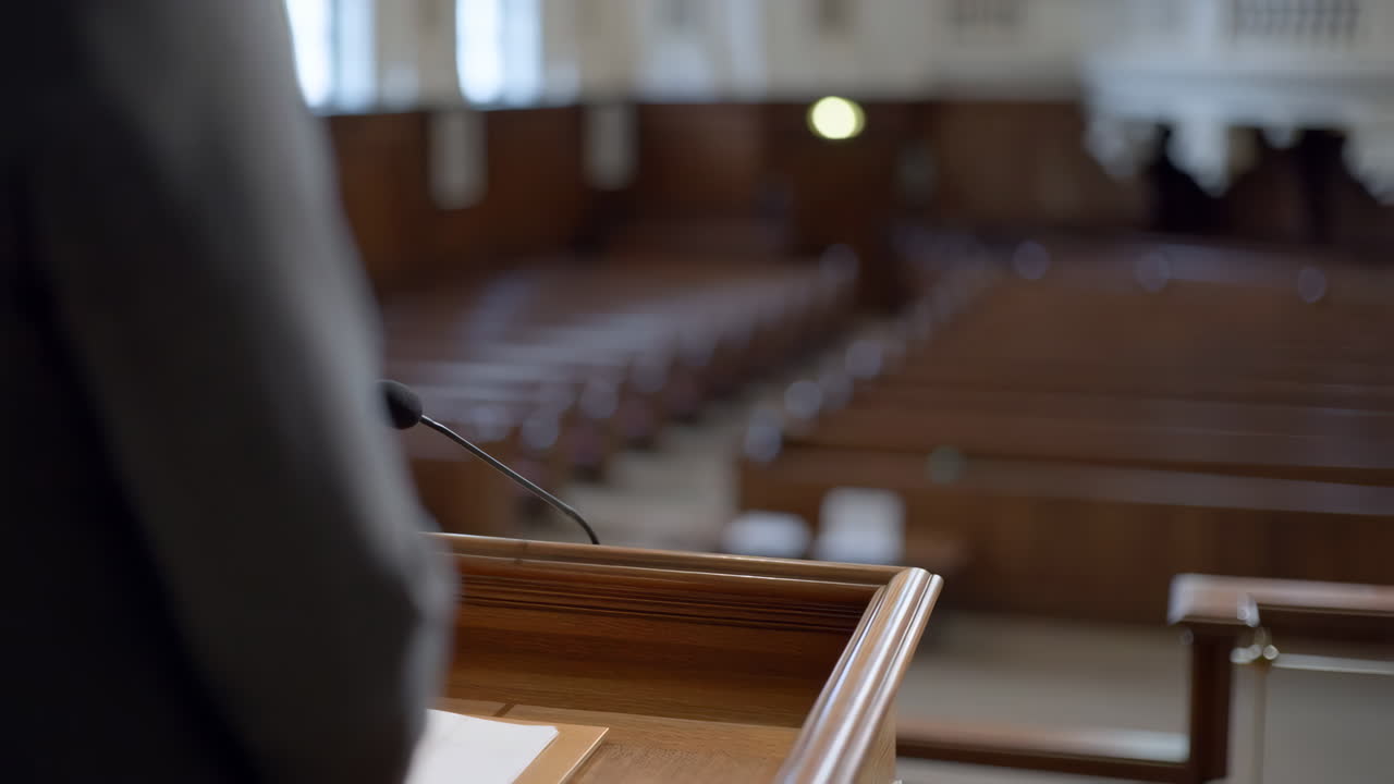 Person speaking at a podium in an empty hall