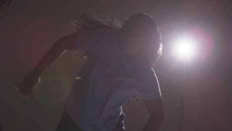 backlit studio shot of young woman dancer being filmed dancing in front of spotlight 1