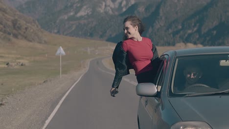 car drives along long road with lady leaning out of window