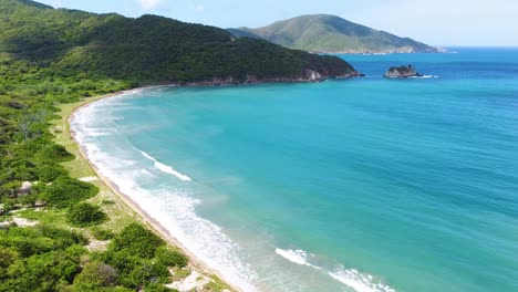 Un-Dron-Se-Acerca-A-Una-Playa-En-El-Parque-Nacional-Tayrona,-En-Las-Estribaciones-De-La-Sierra-Nevada-De-Santa-Marta,-La-Montaña-Costera-Más-Alta-Del-Mundo-Ubicada-En-Colombia,-Sudamérica.