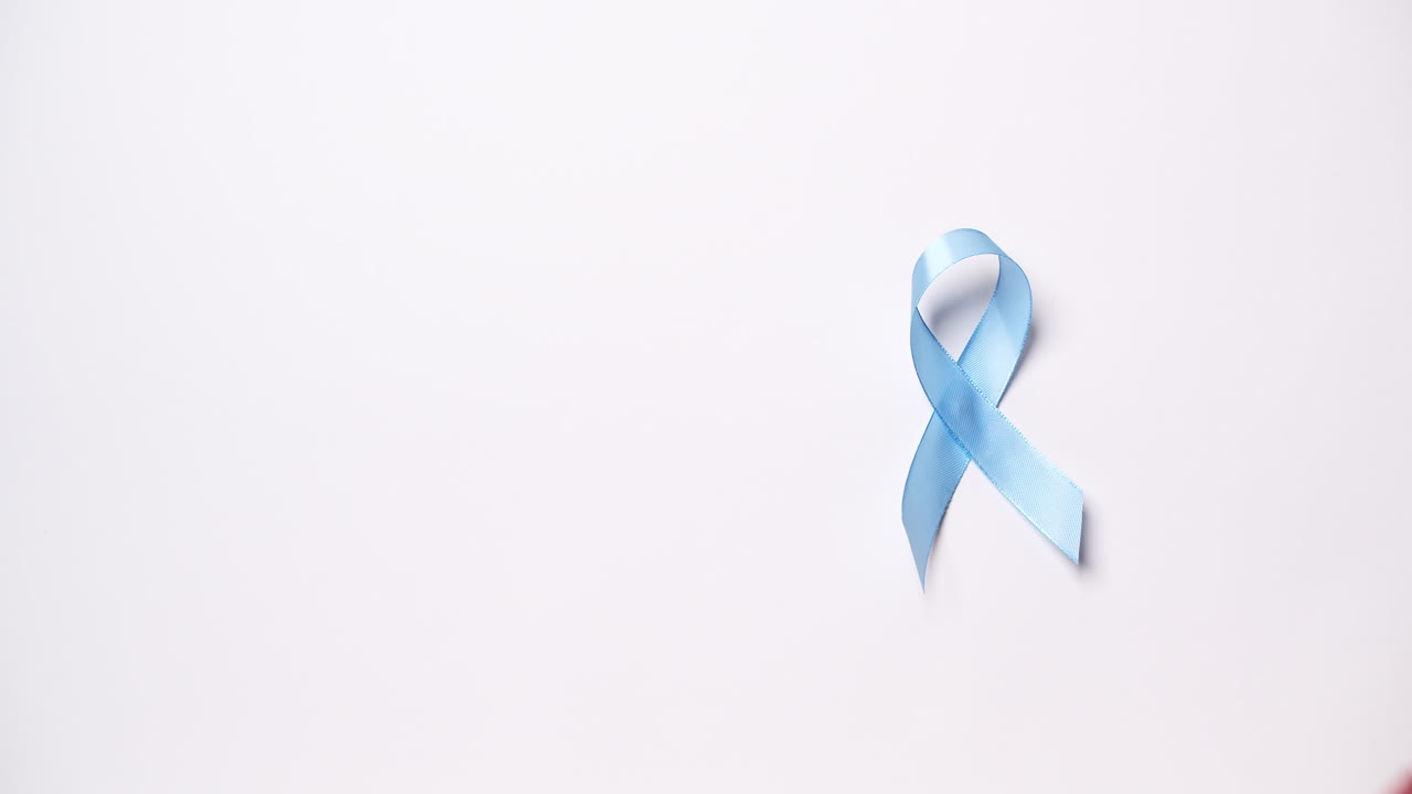 деталь мужской руки, размещающей ленту светло-голубого цвета на белом фоне