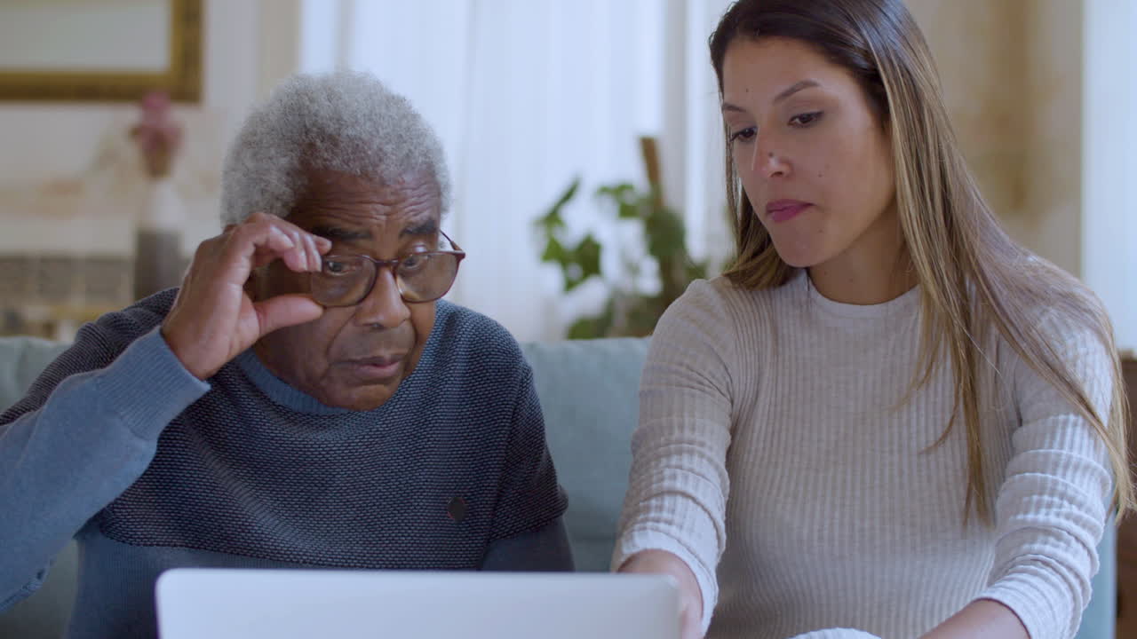 una chica bonita ayudando al abuelo con la computadora portátil.