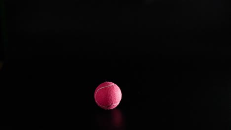 a tennis ball bounces in a dark setting